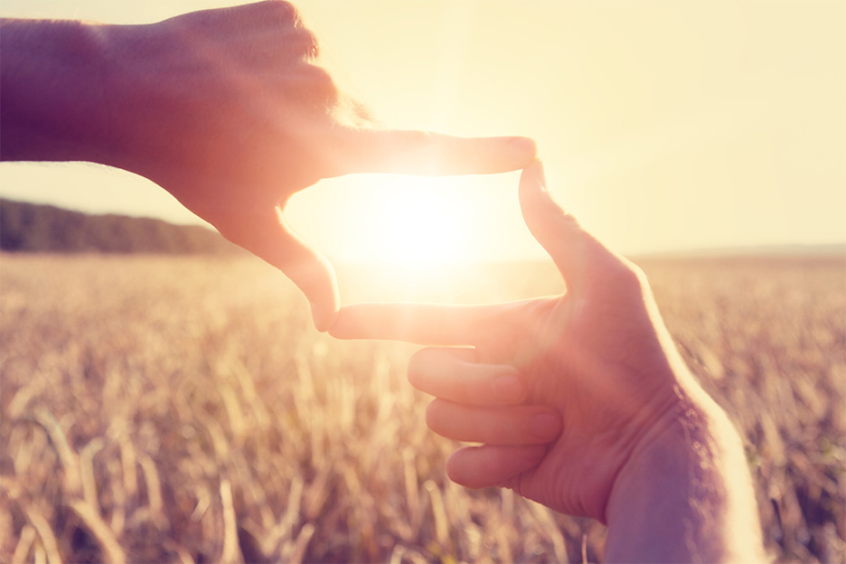 Hands making a picture frame around a sunset for guided imagery and visualisation