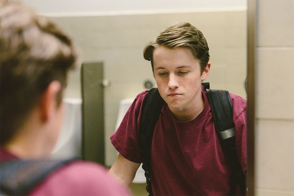 Mirror reflection of a teenage boy looking down - troublesome teenagers